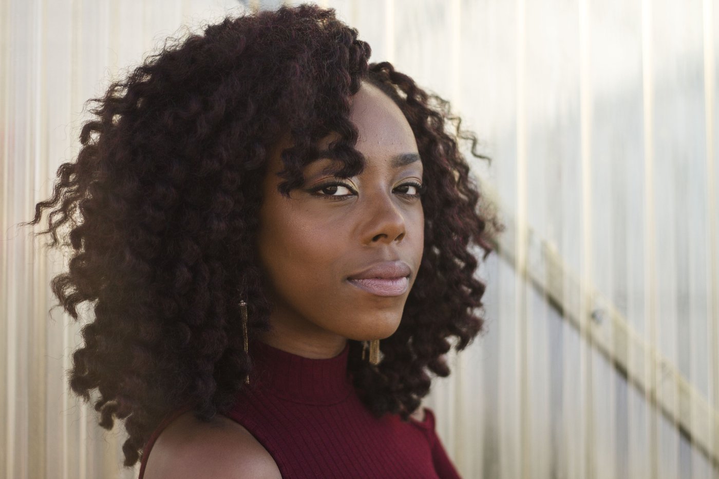 Portrait of a woman with voluminous curly hair in front of a busy background